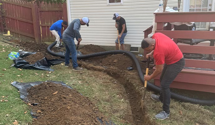 Yard drainage and French drain installation services A team of workers digging a trench and installing a French drain in a backyard