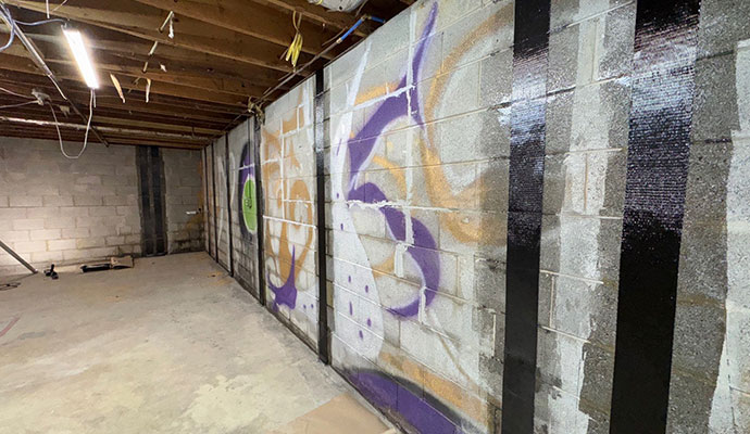 Foundation repair on a basement concrete block wall reinforced with vertical carbon fiber straps.