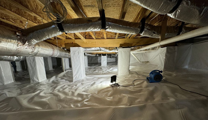 A thick white plastic vapor barrier covers a clean encapsulated crawlspace