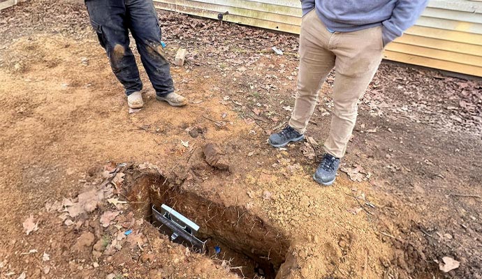 Technicians inspecting an earth anchor plate for foundation stabilization