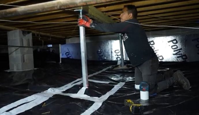 Technician installing an power post to support beam in a crawl space