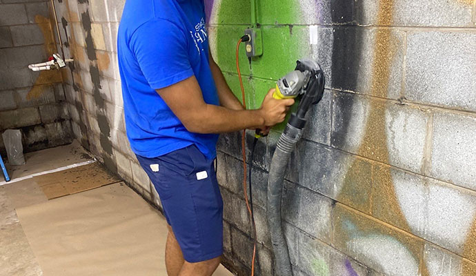 Wall repair service using professional equipment Wall repair in progress with grinder and dust collection equipment