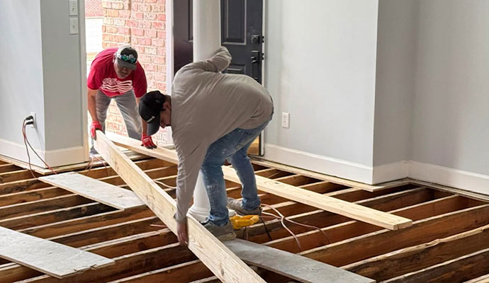 Wood floor installing service over exposed joists Two workers installing wood flooring over exposed joists