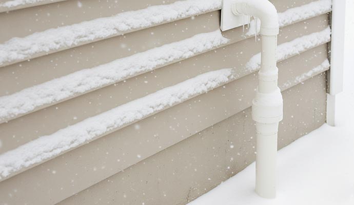 Exterior sump pump discharge pipe frozen with icicles in winter