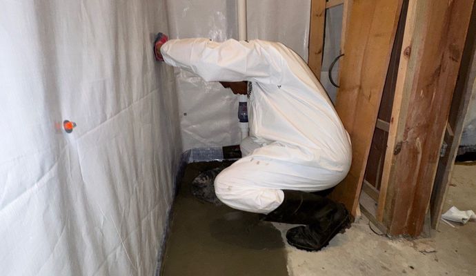 A professional of Crawlspace Titans adding cement to basement drain system
