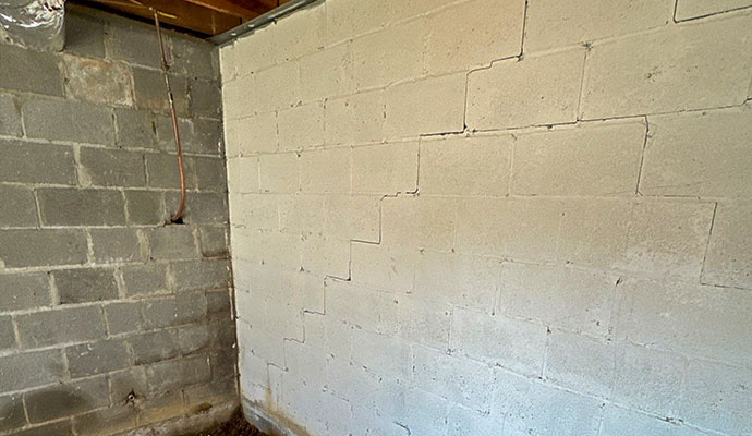 Visible stair-step cracks in a concrete block of a basement foundation wall