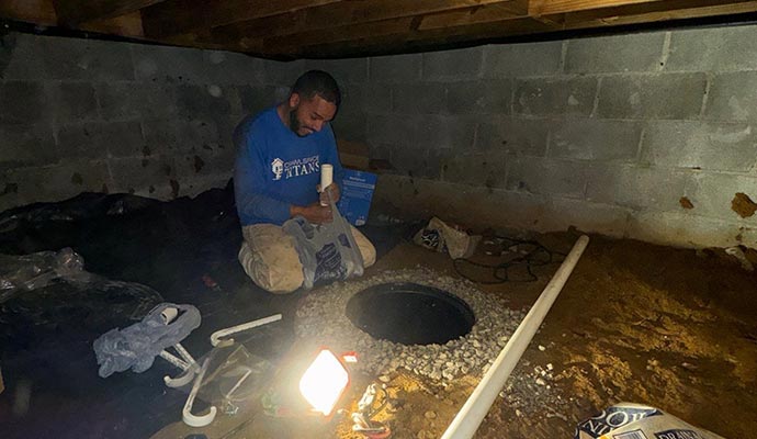 A professional of Crawlspace Titans installing sump-pump battery backup system