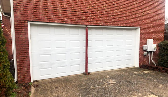 Temporary support post holding up a sagging garage door lintel with cracked brickwork