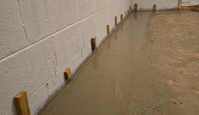 Freshly poured concrete patching a trench along the perimeter